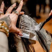 Person getting hair colored with a brush and foil in a salon setting